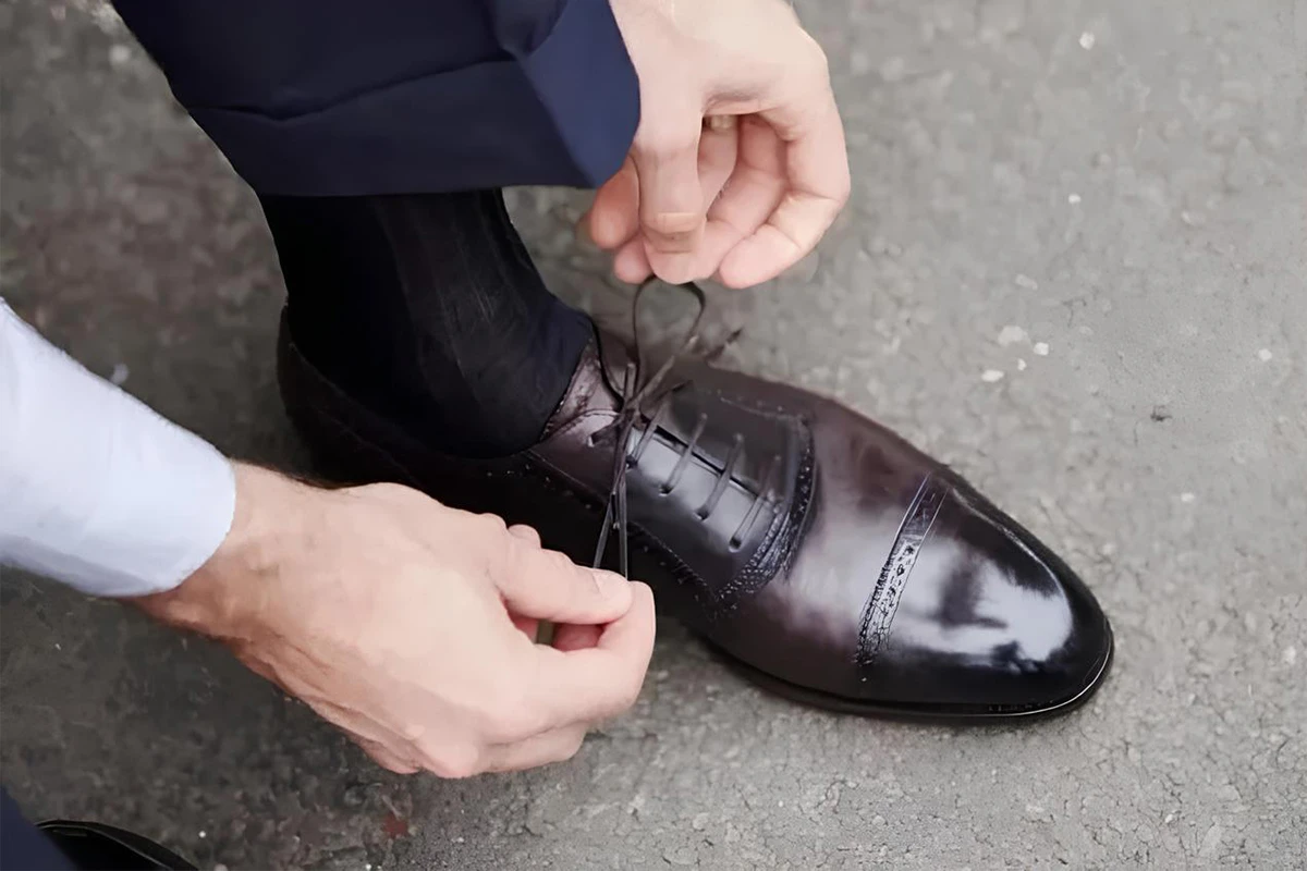 男士為棕色牛津皮鞋繫好鞋帶